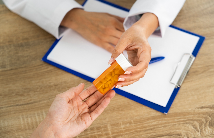 Top view of a hand handing over an orange medicine container